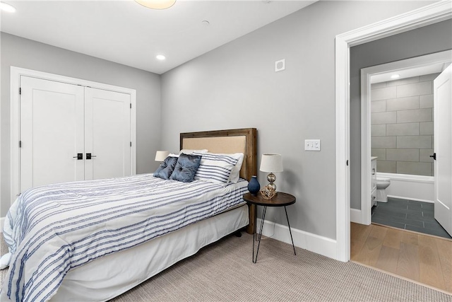 bedroom featuring wood finished floors, baseboards, a closet, ensuite bathroom, and recessed lighting