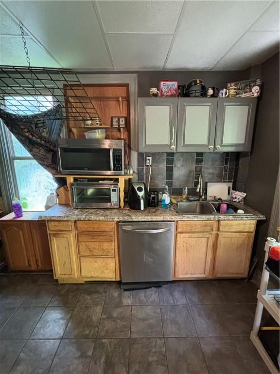 kitchen featuring sink, a drop ceiling, decorative backsplash, dark tile patterned floors, and stainless steel appliances