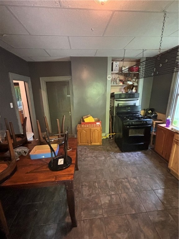 dining area with a drop ceiling and dark tile patterned flooring