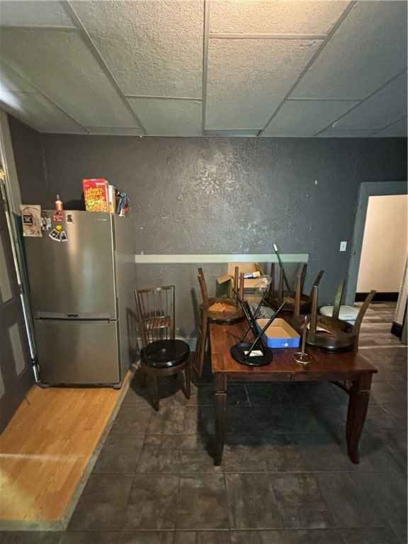 dining area with a drop ceiling and tile patterned flooring