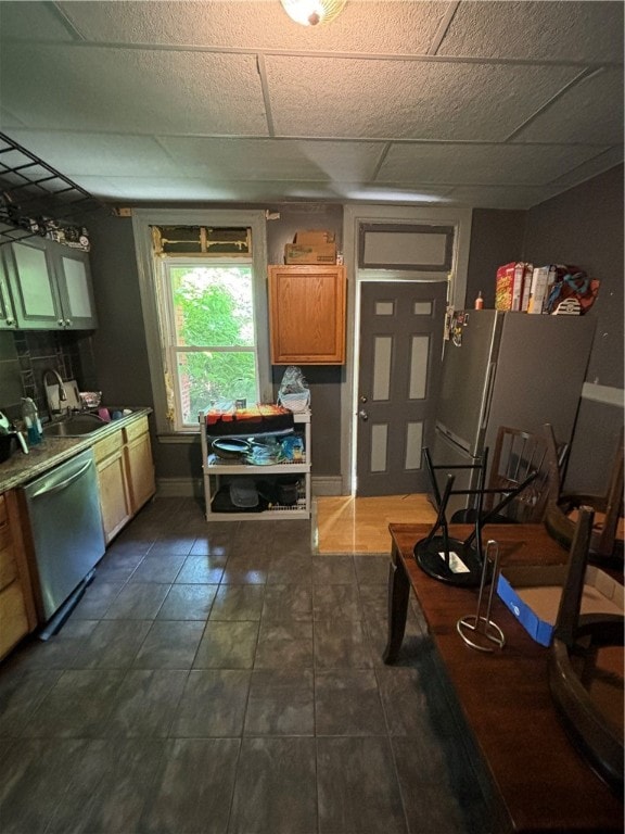 kitchen featuring appliances with stainless steel finishes, a paneled ceiling, sink, and dark tile patterned flooring