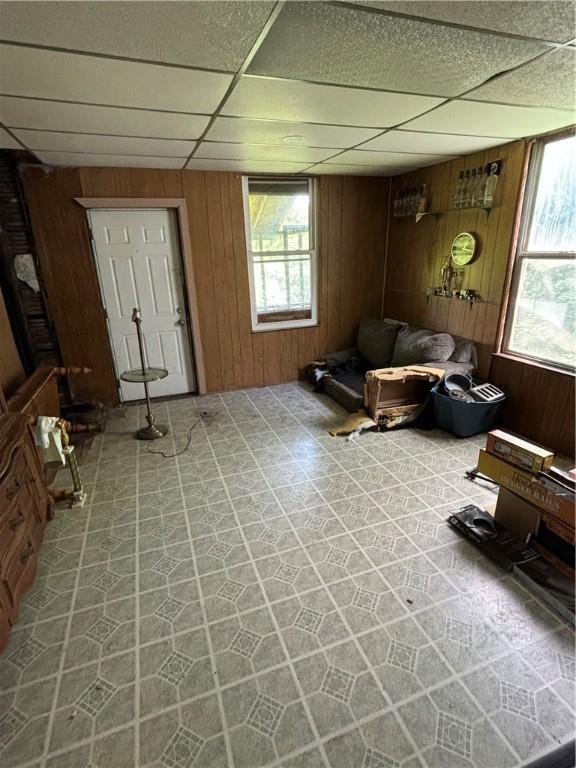 tiled living room with wood walls and a drop ceiling