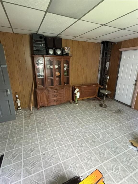 interior space featuring wood walls, a paneled ceiling, and light tile patterned floors