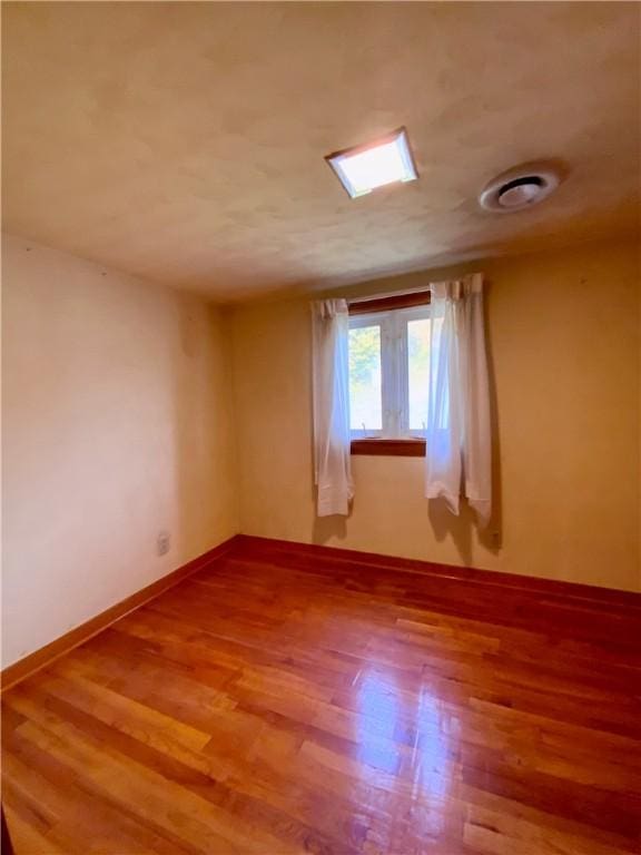 spare room featuring baseboards and wood finished floors