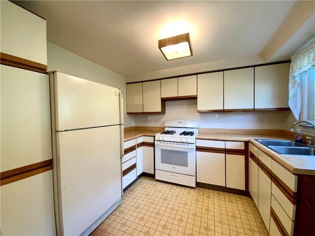 kitchen featuring light countertops, white appliances, a sink, and white cabinets