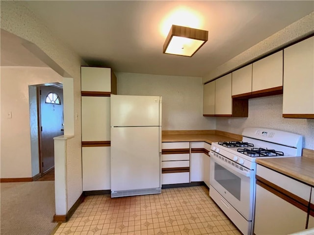 kitchen with white appliances, baseboards, white cabinets, light countertops, and light floors