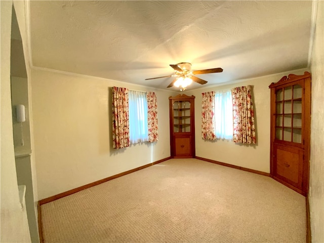 spare room featuring carpet, ceiling fan, a textured ceiling, and ornamental molding