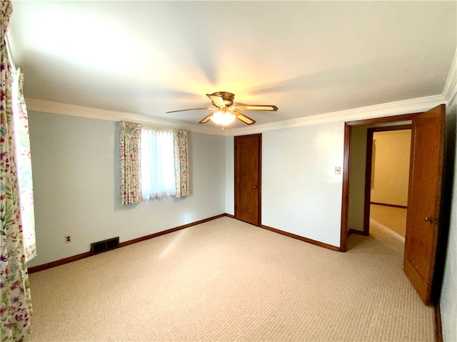 empty room featuring ceiling fan, carpet floors, and ornamental molding