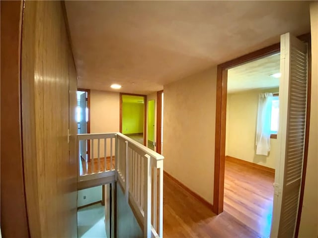 hallway with baseboards, light wood finished floors, and an upstairs landing