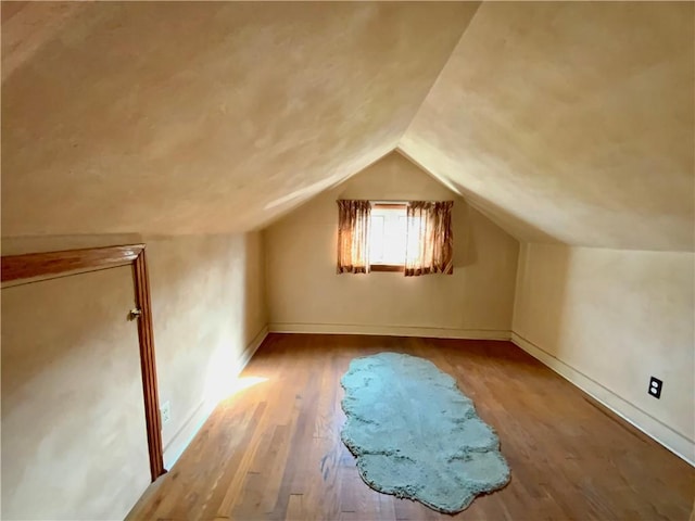 additional living space featuring vaulted ceiling, baseboards, and wood finished floors