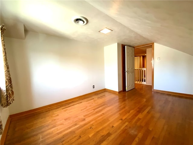 additional living space with lofted ceiling and hardwood / wood-style floors