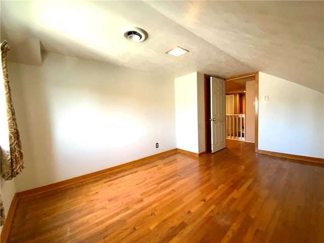 bonus room featuring visible vents, vaulted ceiling, baseboards, and wood finished floors