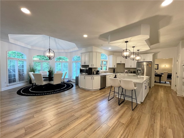 kitchen featuring a center island, light wood-type flooring, decorative light fixtures, and appliances with stainless steel finishes