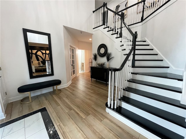 stairs featuring a towering ceiling and wood-type flooring