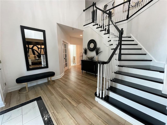 stairs featuring hardwood / wood-style flooring and a towering ceiling