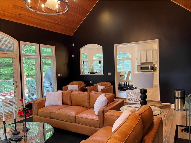 living room featuring light hardwood / wood-style floors, wood ceiling, a notable chandelier, high vaulted ceiling, and a healthy amount of sunlight