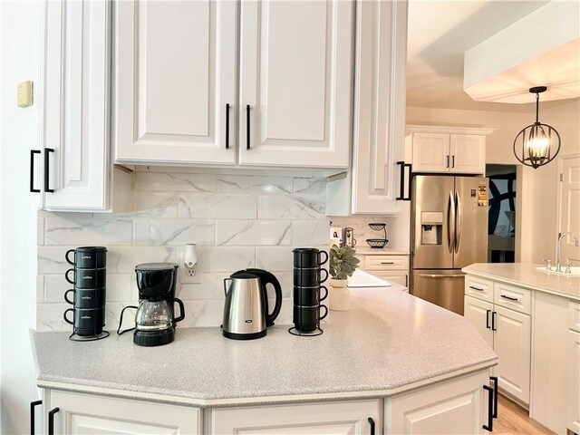 kitchen featuring stainless steel refrigerator with ice dispenser, hanging light fixtures, backsplash, and white cabinets