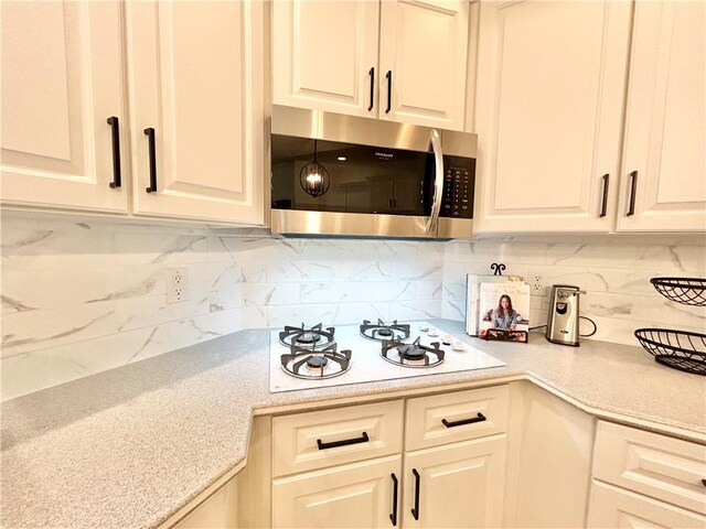 kitchen featuring white gas stovetop, backsplash, and light stone countertops