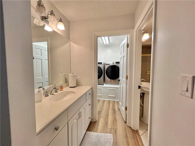 bathroom with wood-type flooring, washer and clothes dryer, and vanity