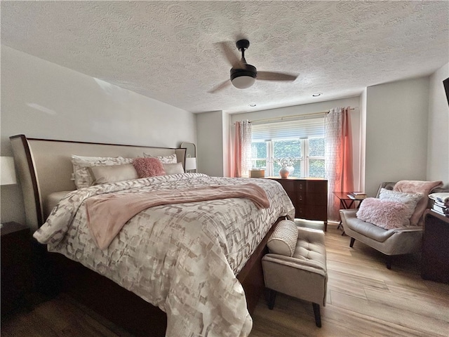 bedroom featuring hardwood / wood-style flooring, ceiling fan, and a textured ceiling