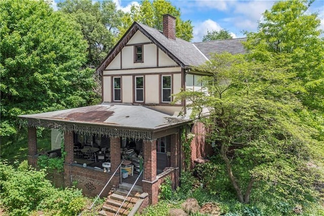 view of front of home featuring a chimney, brick siding, and stucco siding