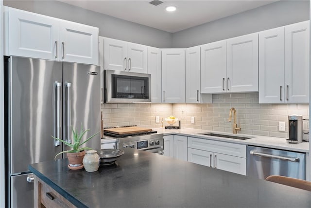 kitchen with backsplash, sink, high quality appliances, and white cabinets