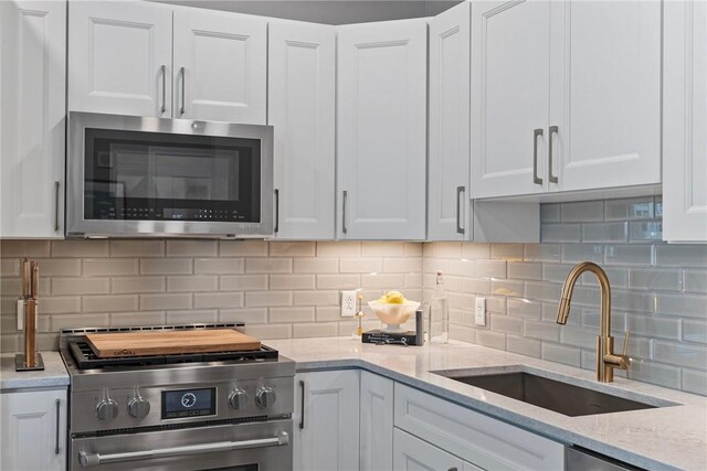 350 Oliver Ave Unit 908, Downtown Pgh, PA 15222 - kitchen with white cabinets, backsplash, stainless steel appliances, and a sink