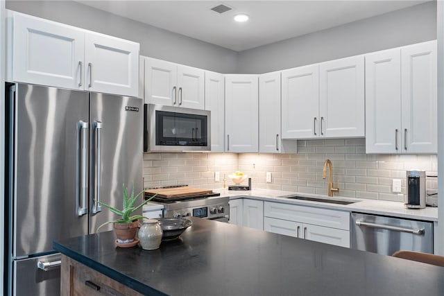 kitchen featuring stainless steel appliances, white cabinets, backsplash, and sink