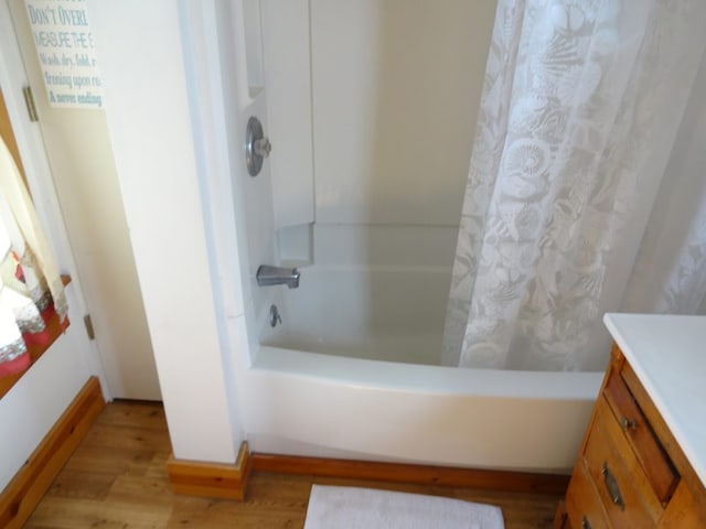 bathroom with hardwood / wood-style floors, vanity, and shower / tub combo with curtain