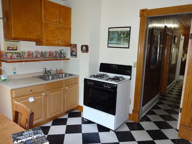 kitchen with sink, dark tile flooring, and white range with gas cooktop