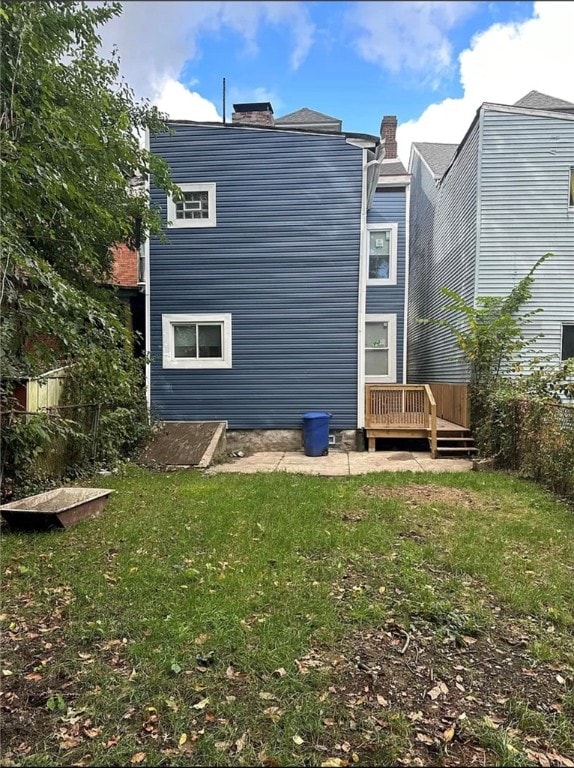 back of property featuring a wooden deck and a lawn