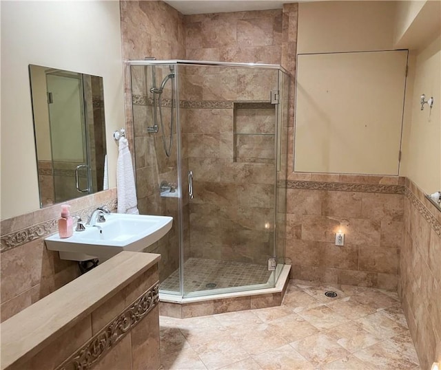 bathroom featuring a shower with door and sink