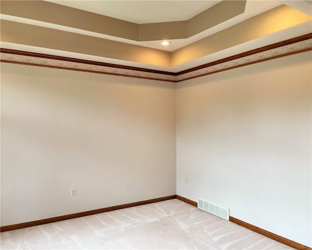 carpeted spare room featuring a tray ceiling