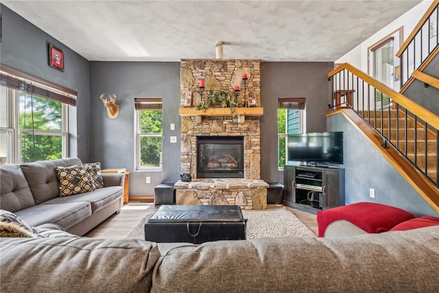 living room with a stone fireplace and light hardwood / wood-style flooring