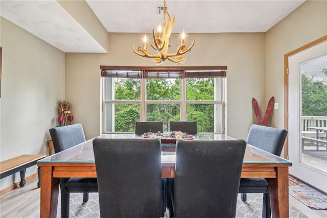 dining area with light hardwood / wood-style floors and an inviting chandelier