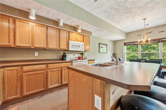 kitchen featuring sink, white appliances, a kitchen island with sink, and a chandelier