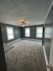 carpeted spare room featuring a paneled ceiling and ceiling fan