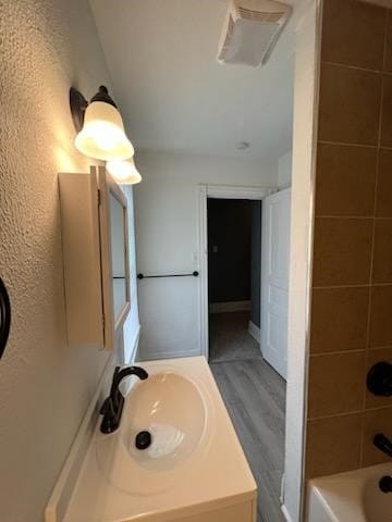 bathroom featuring hardwood / wood-style floors, sink, and tiled shower / bath