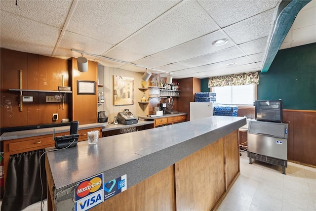 kitchen with a drop ceiling and wooden walls