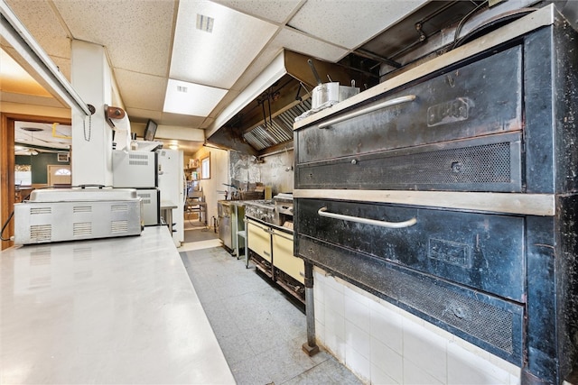 basement featuring light tile floors and a drop ceiling