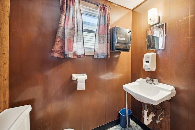 bathroom featuring sink, wood walls, and toilet