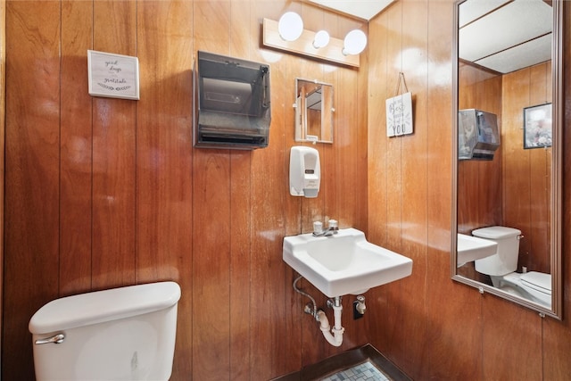 bathroom featuring wood walls, sink, and toilet