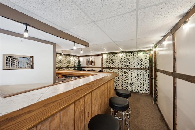 bar featuring tile counters and a drop ceiling