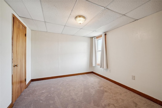 carpeted spare room featuring a drop ceiling