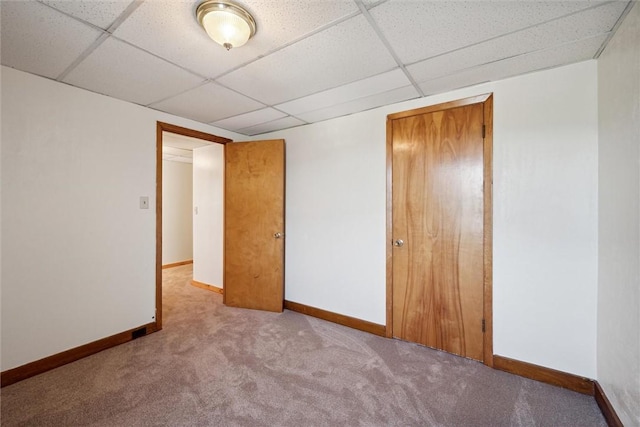 unfurnished bedroom with a closet, light carpet, and a drop ceiling