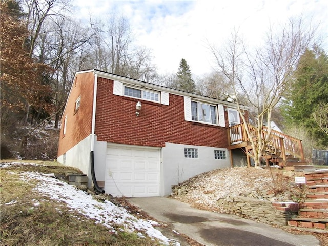 snow covered property with a garage and a wooden deck