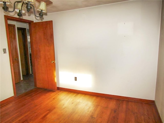 unfurnished room featuring hardwood / wood-style flooring and a notable chandelier