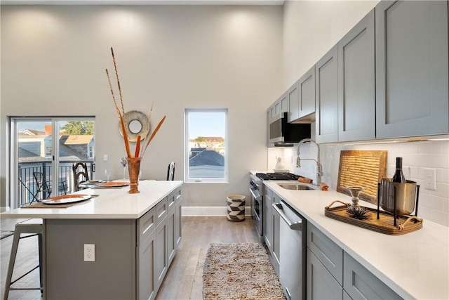 kitchen featuring stainless steel appliances, an island with sink, and gray cabinetry