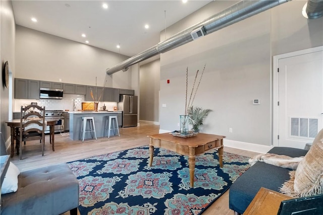 living room with light hardwood / wood-style flooring and a high ceiling