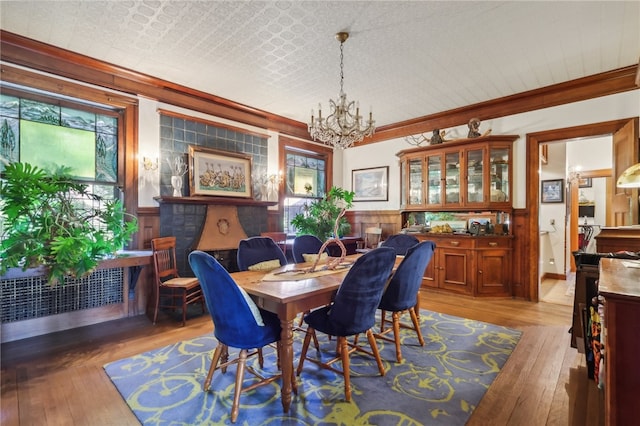 dining area with crown molding, light wood-type flooring, and an inviting chandelier